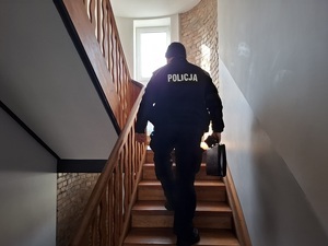 dzielnicowy na klatce schodowej. Idzie schodami do góry