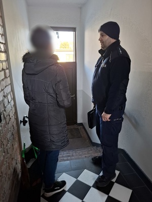 dzielnicowy rozmawiający z kobietą na klatce schodowej
