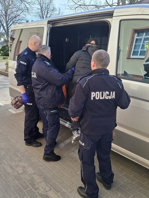 przed nieoznakowanym radiowozem stoją trzej policjanci. Do radiowozu wchodzi zatrzymany mężczyzna