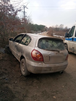 szary nissan almera unieruchomiony przy niewielkiej skarpie. Obok stoi policyjny oznakowany radiowóz
