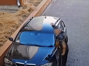 przy bmw stoi starszy mężczyzna, który robi zamach ręką nad przednią szybą tego auta