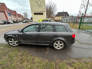 poza jezdnią stoi czarny osobowy samochód. Obok znajduje się policyjny oznakowany radiowóz