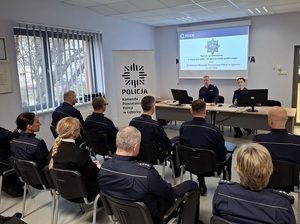 w auli przy stole siedzą Komendant Powiatowy Policji w Lęborku i Zastępczyni Komendanta Wojewódzkiego Policji w Gdańsku. Komendant omawia wyniki osiągnięte w ubiegłym roku. Naprzeciw siedzą policjanci