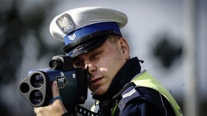 policjant ruchu drogowego mierzy prędkość pojazdów za pomocą ręcznego miernika prędkości