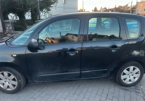 na parkingu stoi czarny citroen c3. Obok stoi policyjny oznakowany radiowóz