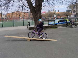 na placu szkolnym dziewczynka przejeżdża rowerem przez pochylnię