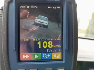 ekran ręcznego miernika prędkości, na którym widać szare osobowe audi i wyświetloną prędkość 108 km/h