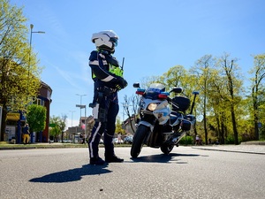 na ulicy przy oznakowanym motocyklu stoi policjant ruchu drogowego
