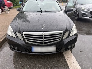 na mokrej po deszczu jezdni przy chodniku stoi czarny osobowy mercedes