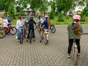 w policyjnym miasteczku ruchu drogowego znajdują się dzieci na rowerach . Przed nimi stoją policjanci ruchu drogowego