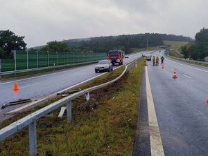droga S6. Miejsce zdarzenia drogowego. Bariery ochronne rozdzielające pasy ruchu są wygięte. Na jezdni stoi nieoznakowany policyjny radiowóz, za nim wóz straży pożarnej. Po drugiej stronie na jezdni stoją strażacy. Na pasach ruchu w obu kierunkach, są ustawione pachołki