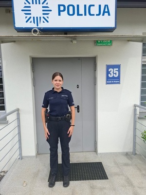przed posterunkiem policji stoi policjantka w letnim umundurowaniu służbowym