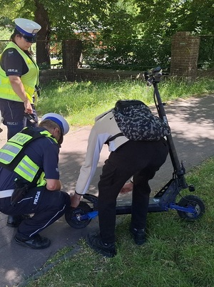na ścieżce rowerowej policjantka i policjant ruchu drogowego kontrolują użytkownika hulajnogi elektrycznej