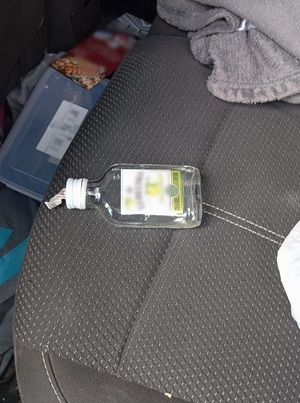 na tylnym siedzeniu samochodu leży częściowo opróżniona mała butelka wódki, tzw. "małpka"