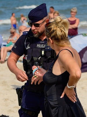 na plaży nad morzem policjant rozmawia z plażowiczką