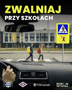 zdjęcie przedstawiające widok z perspektywy kierowcy na przejście dla pieszych, po którym idą chłopiec i dziewczynka z plecakami szkolnymi na plecach. Na górze napis o treści Zwalniaj przy szkołach