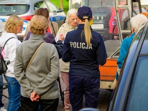 na dworze przy grupie seniorów stoi policjantka