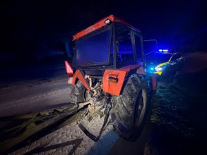 pora nocna. Na drodze stoi stary, zniszczony czerwony ciągnik rolniczy Ursus. Przed nim stoi policyjny radiowóz