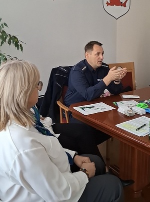 w sali, obok przedstawicielki ZUS, siedzi przy stole policjant, który przemawia i gestykuluje